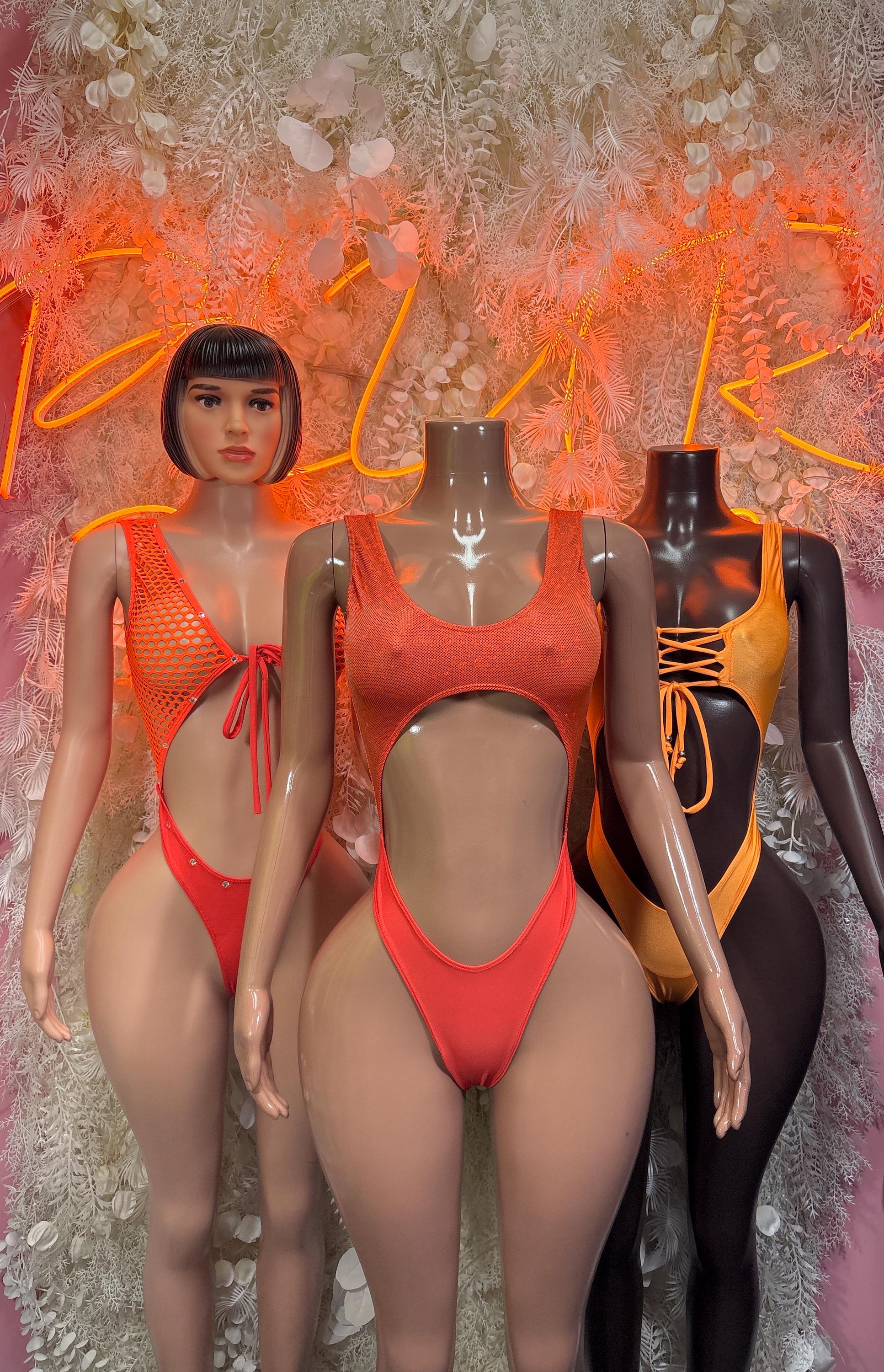 Orange one-piece bodysuit set on mannequins, mixed styles