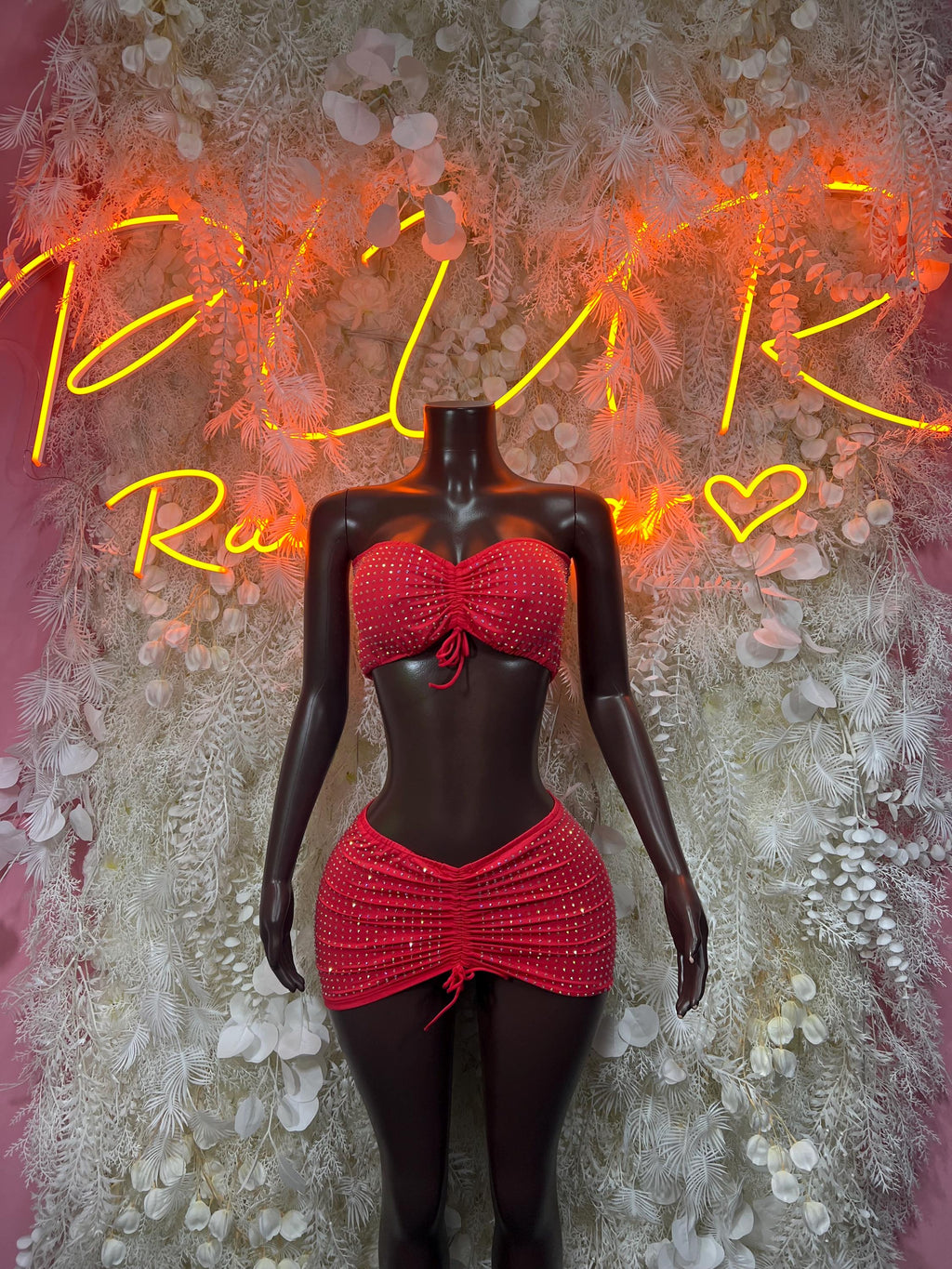 Red rhinestone strapless crop top with bow and matching mini skirt on mannequin