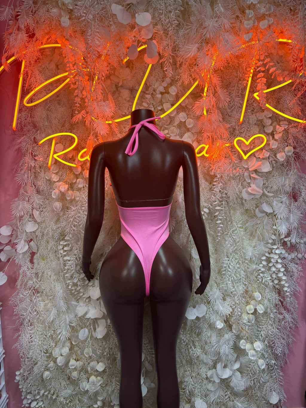 Pink one-piece halter bodysuit with crisscross tie back and high-cut legs