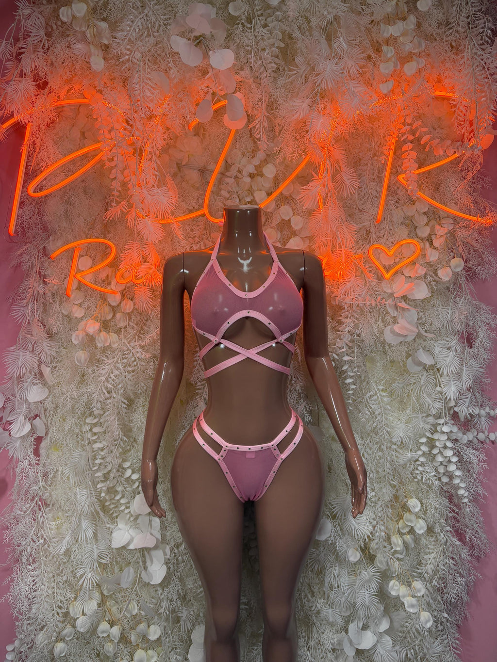Pink strappy rave one-piece bikini on mannequin, crisscross front straps and cutout