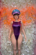 Purple one-piece bodysuit with wide straps and matching sequin cap