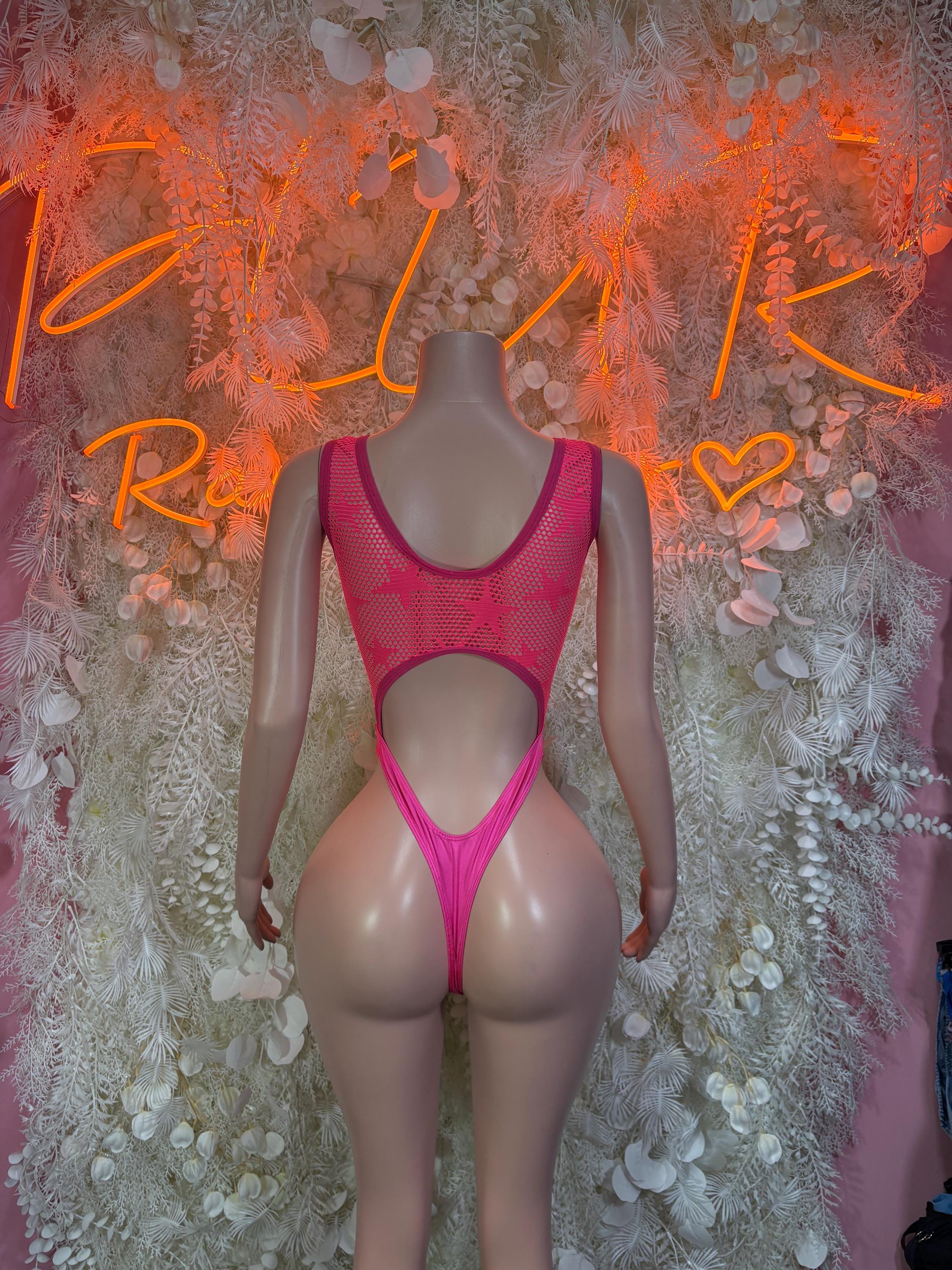 Pink mesh one-piece bodysuit with racerback straps, front cutout, and thong-style leg
