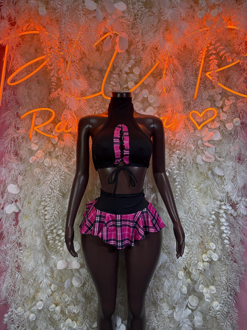 Two-piece rave outfit: black halter crop top with pink plaid mini skirt on mannequin
