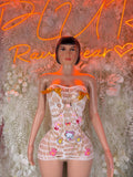 White fishnet mini dress with bandeau neckline and colorful graphic patch details