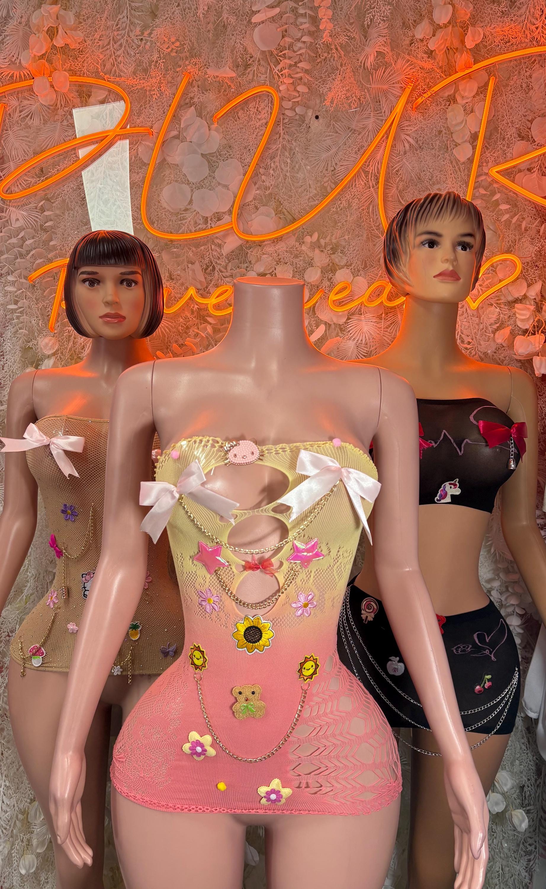 Pink mesh fishnet mini dress with multicolor pinned charms and white ribbon bows