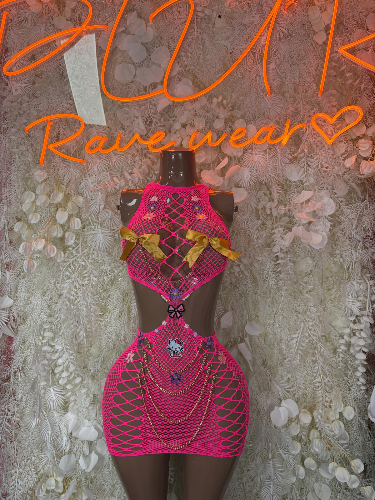 Pink fishnet bodysuit with diamond pattern and matching skirt overlay on mannequin