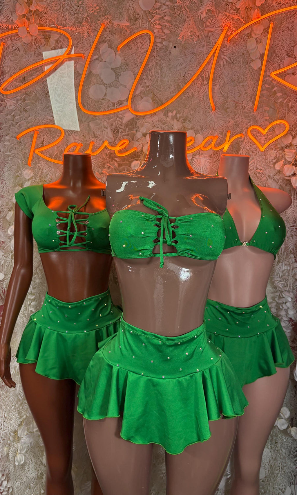 Green two-piece skirt set on mannequins, cropped lace-up tops and flared mini skirts