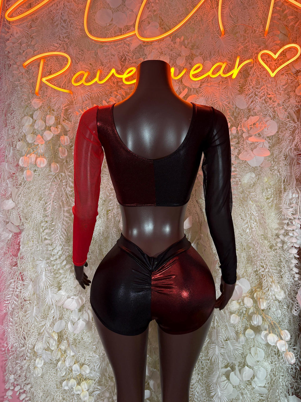 Two-piece rave outfit on mannequin: black bralette crop top with long red sleeves, shorts