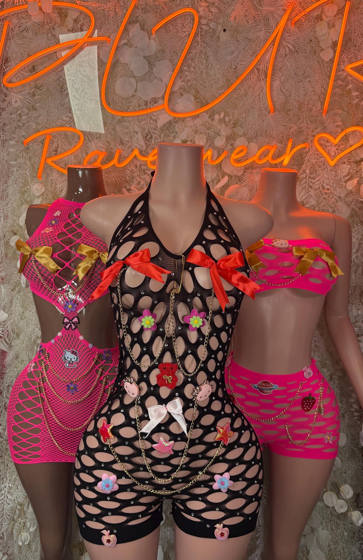 Black fishnet bodysuit with multicolor floral patches, plus pink shorts on mannequin