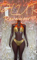 Gold metallic dancewear set with gold bra-style top and high-cut briefs on dark base.