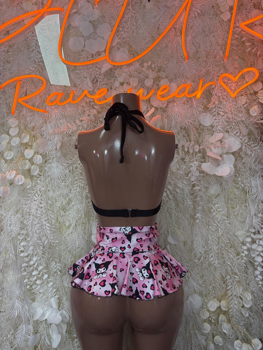 Back view of black tie triangle bra with pink heart-print pleated mini skirt
