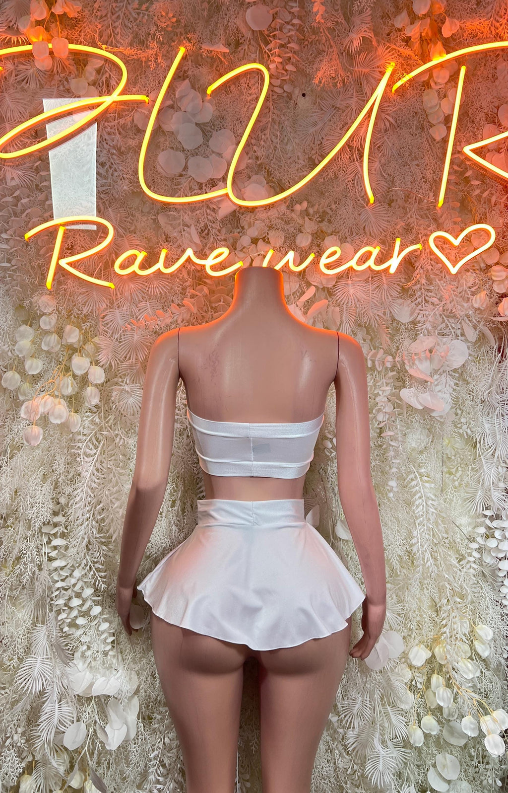 White two-piece rave outfit: back view of bandeau top with thin straps, mini skirt