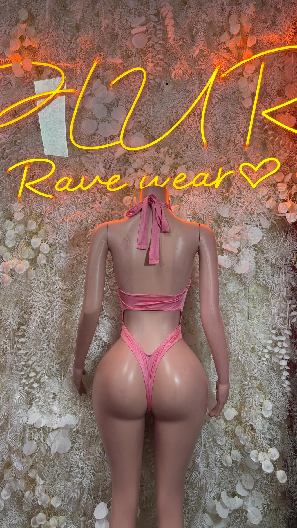 One-piece bodysuit in light pink with open back, halter tie, and sheer-style cutouts