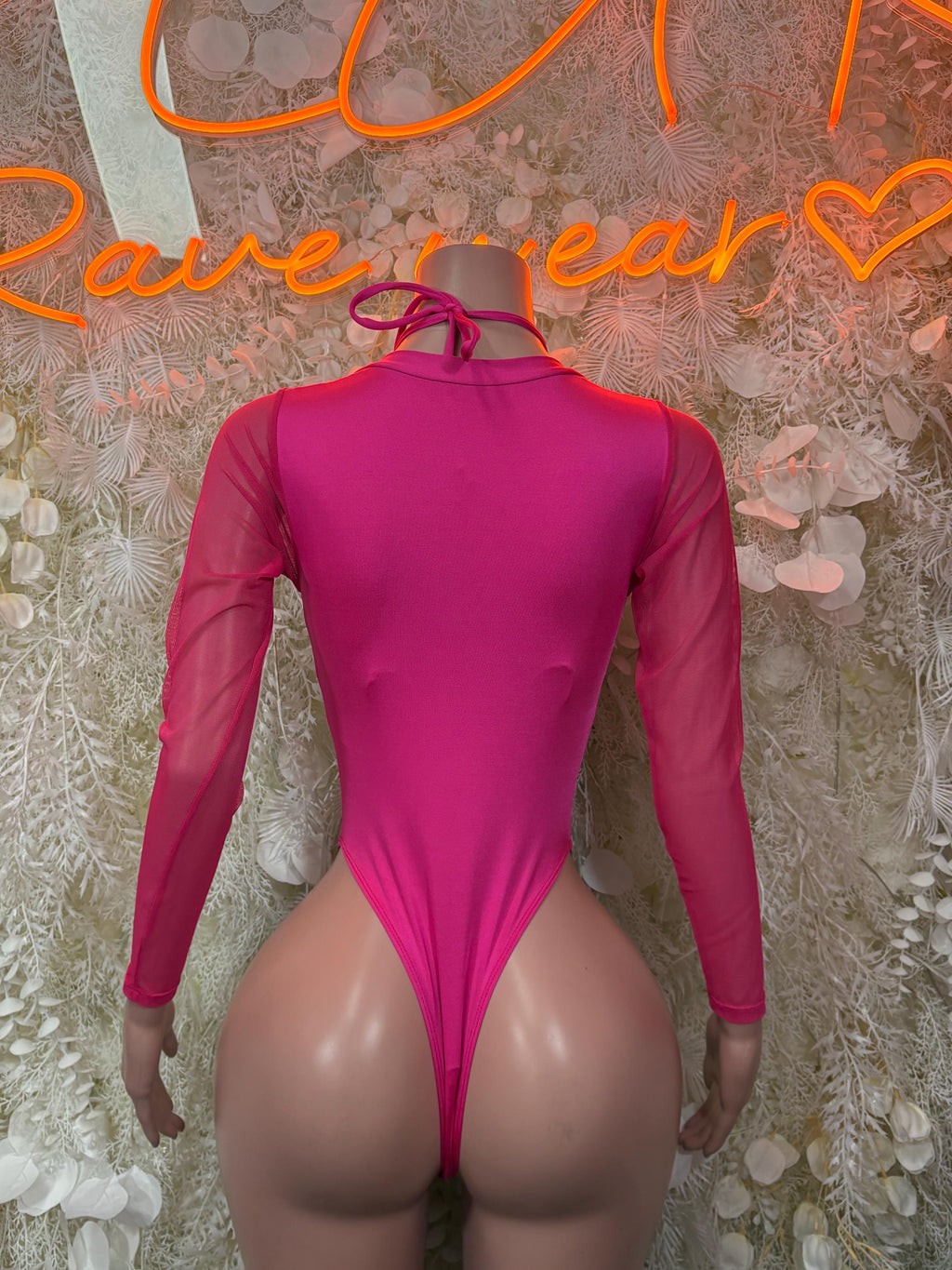 Back view of pink bodysuit with high neckline, long sleeves, and thong-style bottom