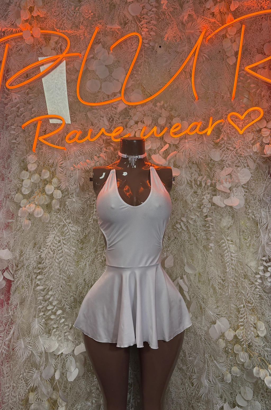 White mini skirt with flared peplum hem on fitted bodice top, sleeveless