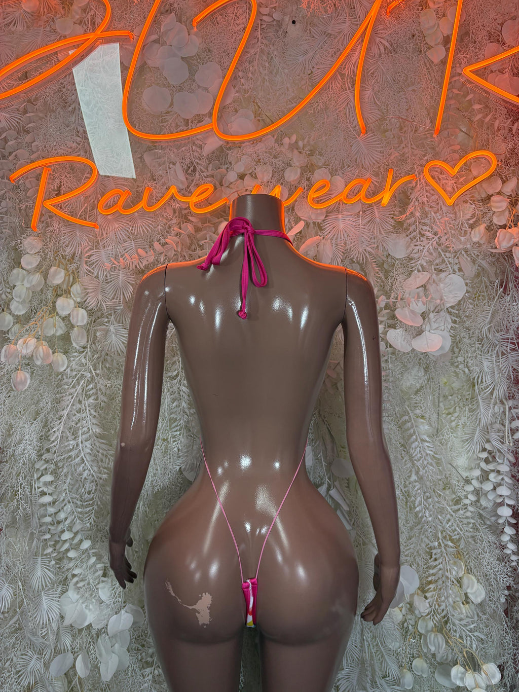 Back view of heart cutout bodysuit with multicolor hearts print and pink string ties