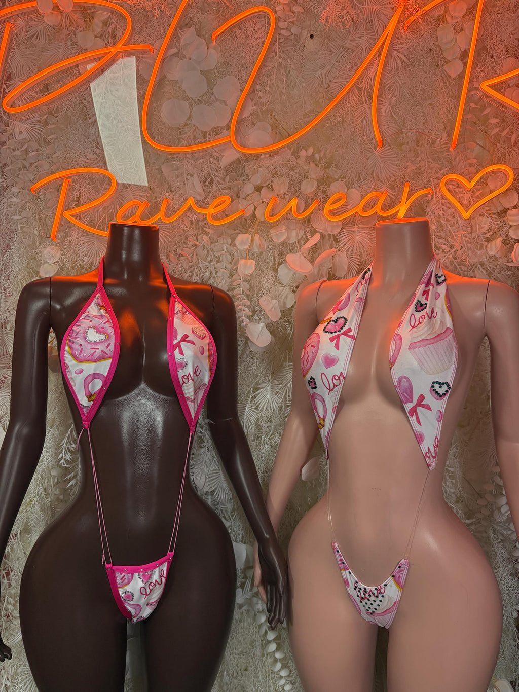 One-piece lingerie bodysuits with pink donut-style print on two mannequins, side-by-side