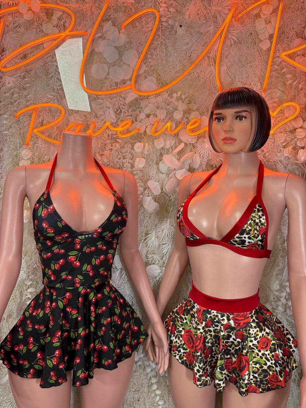 Floral skirt sets on two models: one black, one red bra tops with rose-print skirts