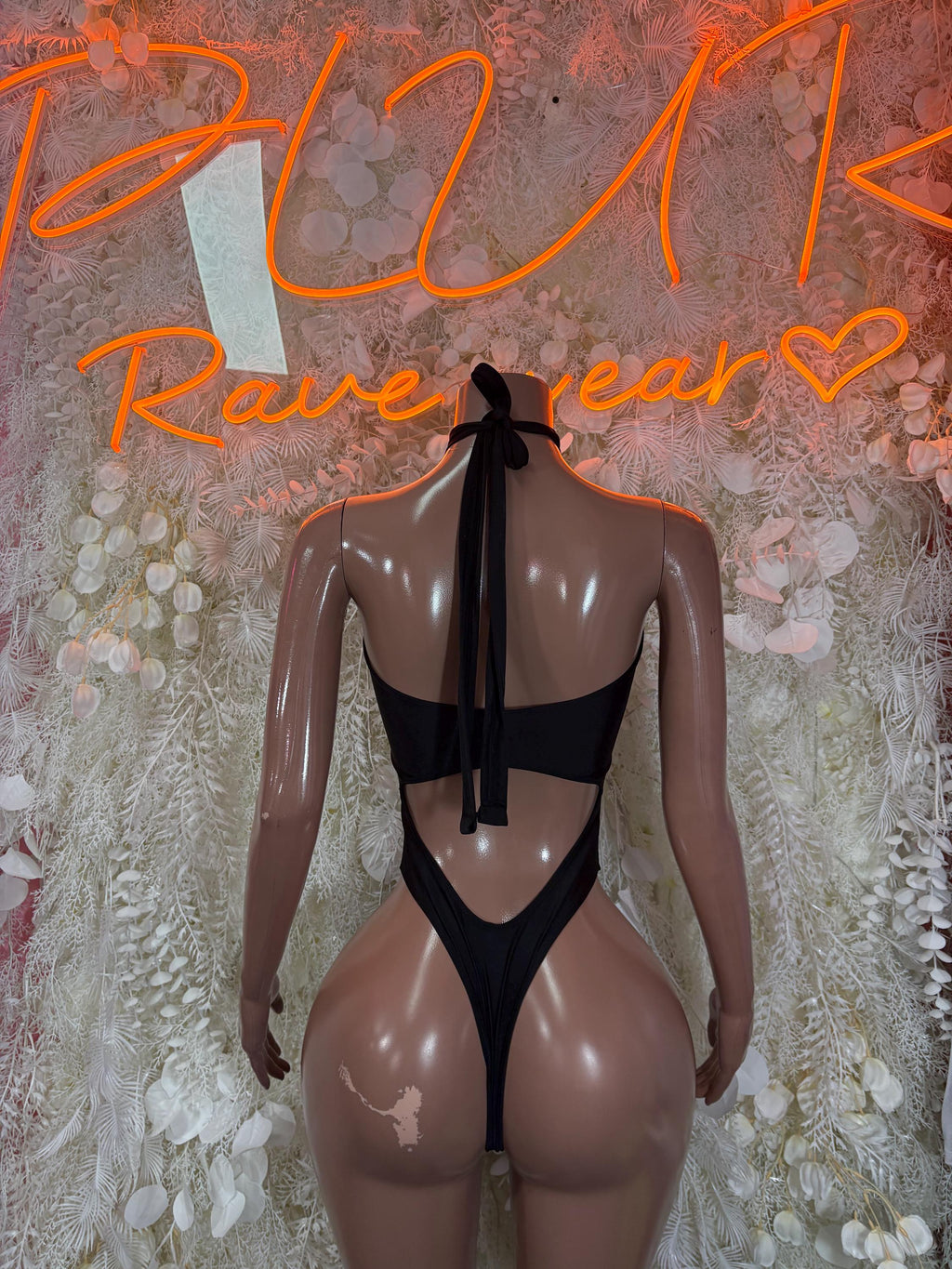 Black open-back one-piece bodysuit with tie-back straps and draped keyhole.