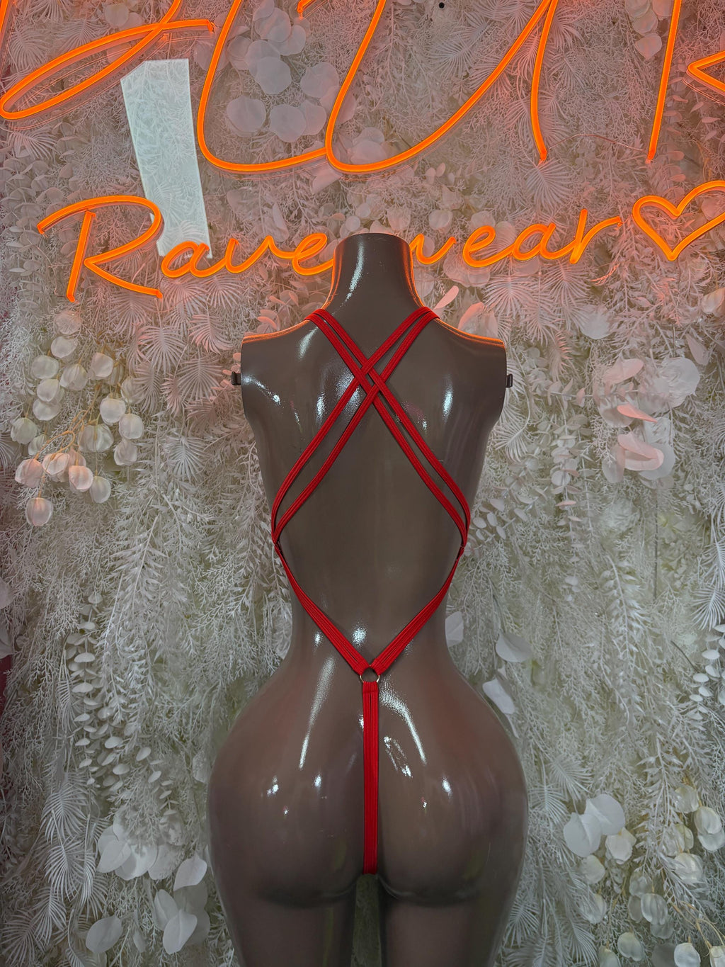 Red-trim bodysuit with crisscross straps and keyhole ring detail at chest