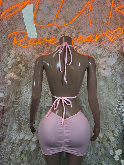 Baby pink mini dress back view with tied halter straps and ruched fitted skirt on mannequin