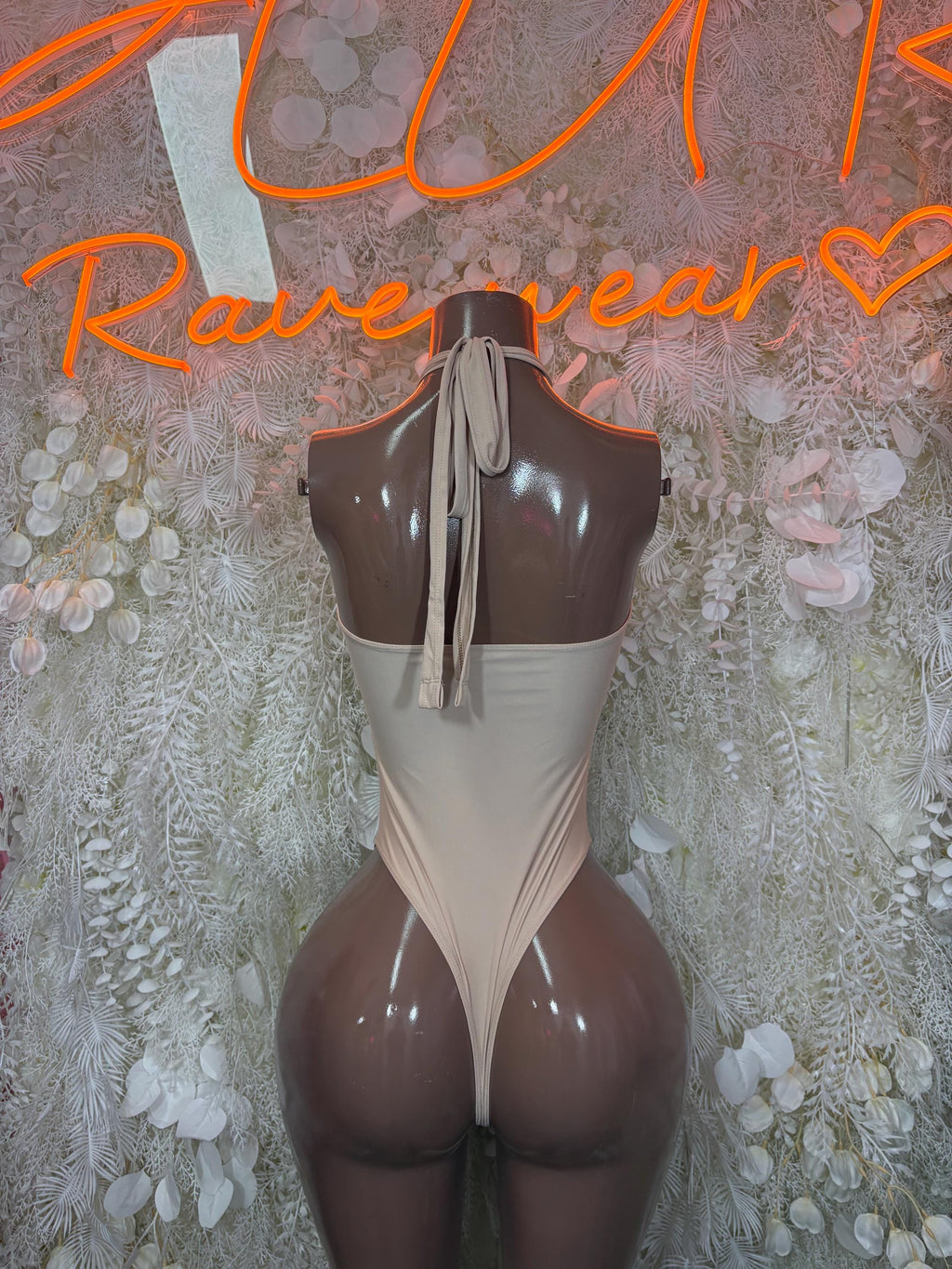 Nude one-piece bodysuit with open back, halter-style straps, cheeky fit