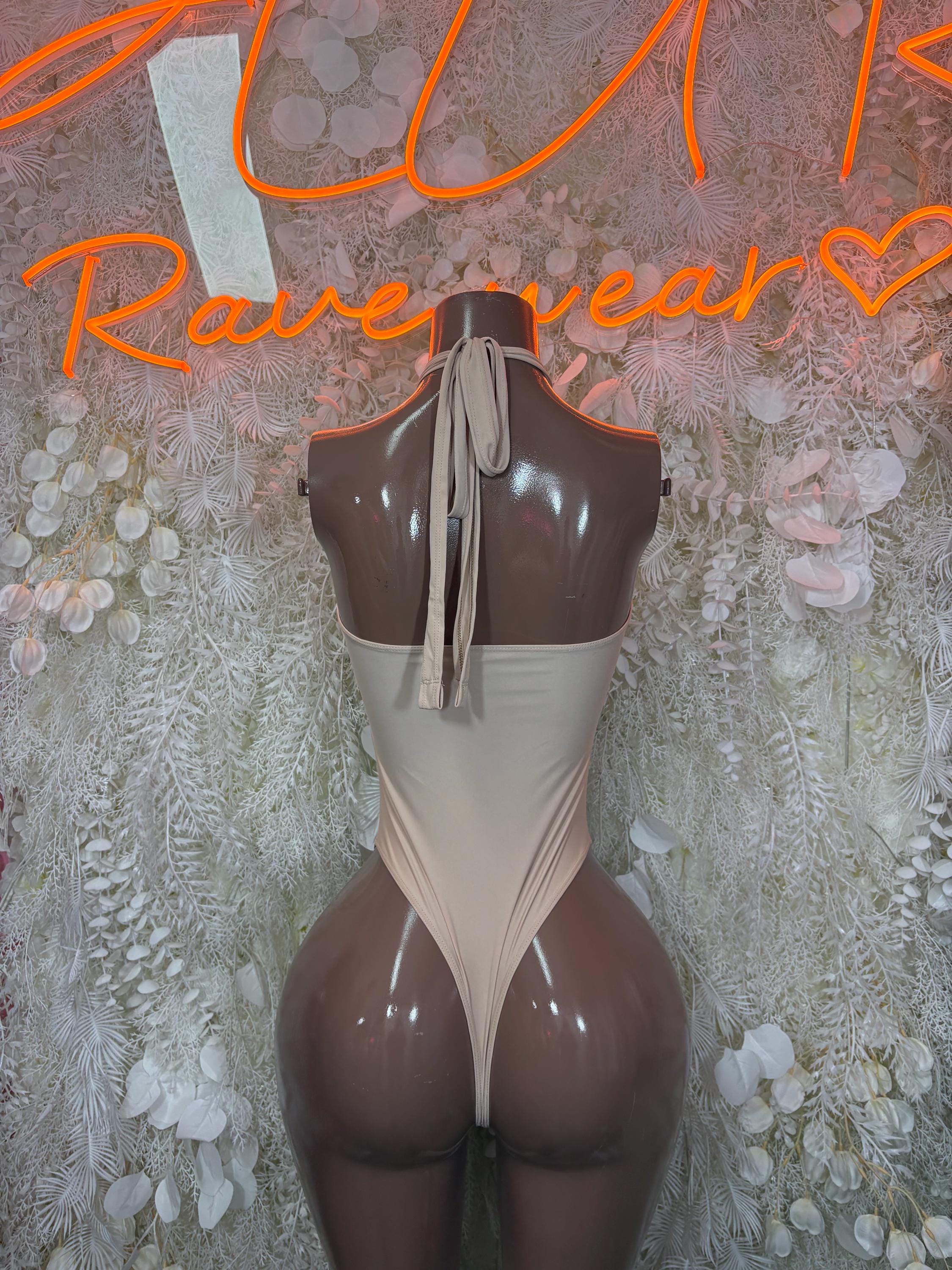 Nude one-piece bodysuit with open back, halter-style straps, cheeky fit