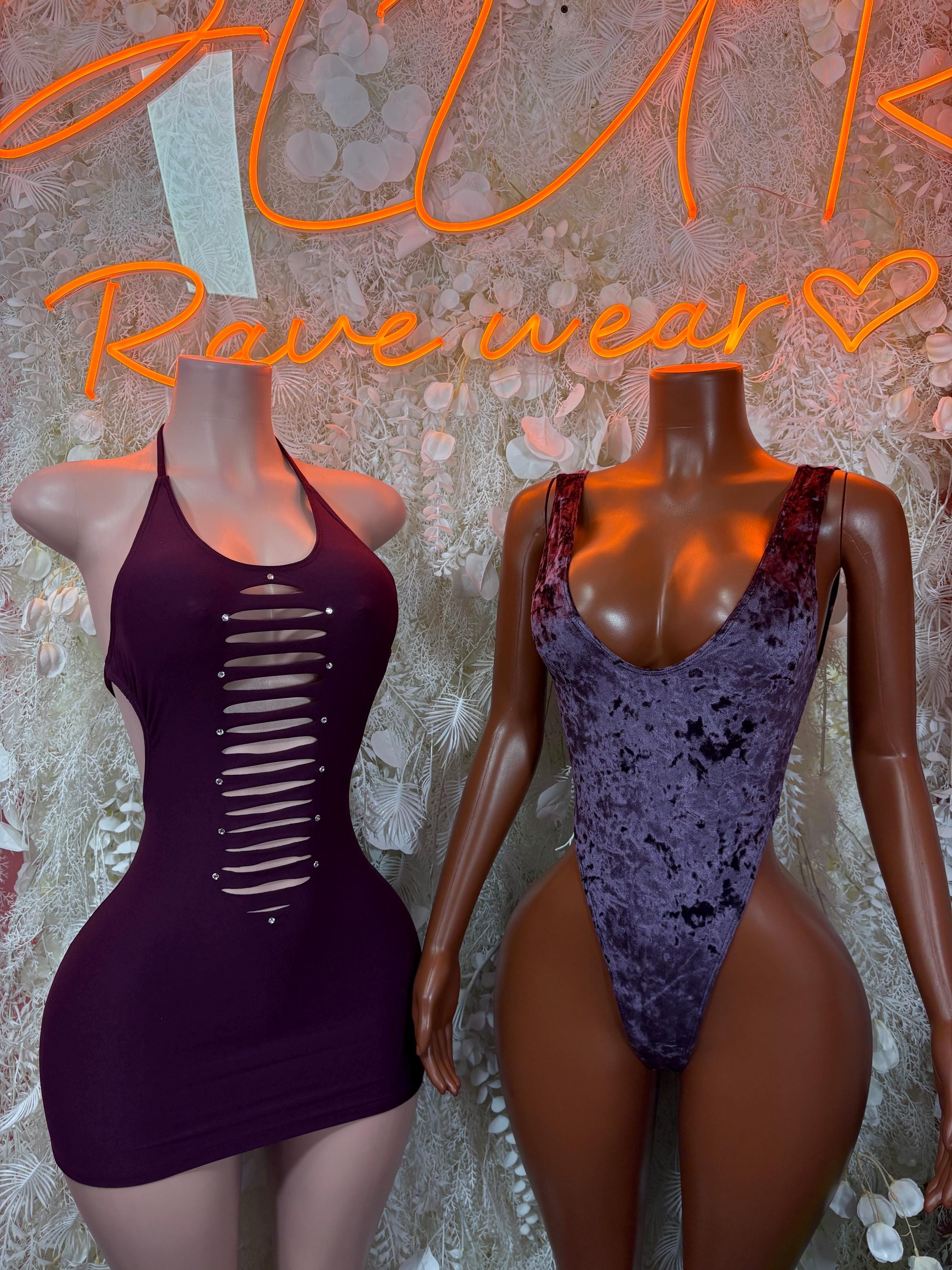 Purple velvet one-piece bodysuit beside dark purple lace-up mini dress