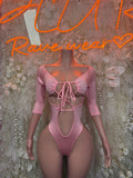 Pink one-piece bodysuit with front lace-up bow and long sleeves