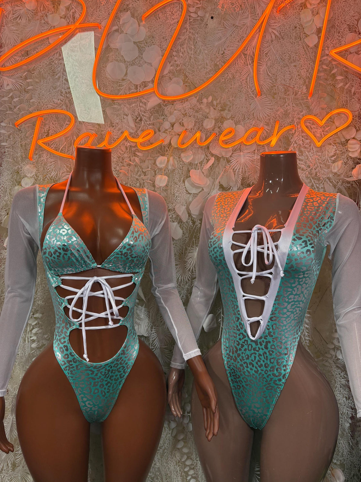 Two aqua cheetah-print bodysuits on mannequins with long sheer sleeves and lace-up fronts