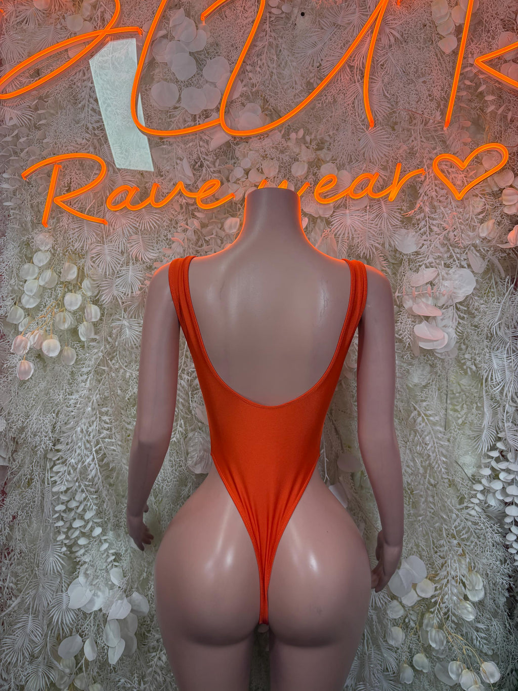 Orange one-piece bodysuit with open back scoop and high-cut legs, sleeveless design