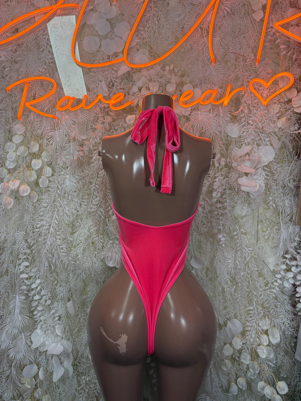Pink halter bodysuit with back tie detail and high-cut coverage