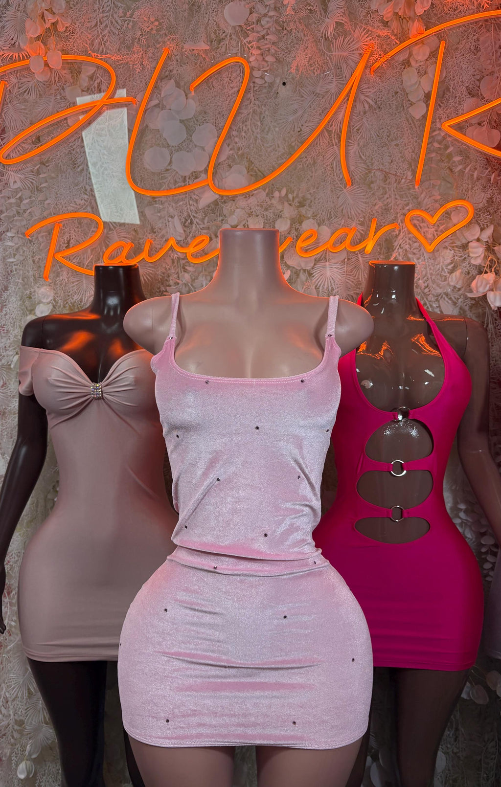 White and hot pink fitted mini dresses with cutout designs on mannequins