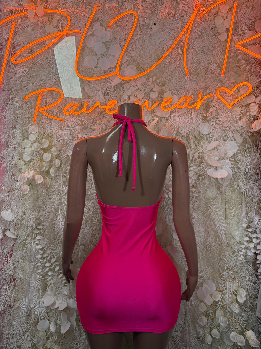 Hot pink fitted mini dress with open back and tie detail on mannequin