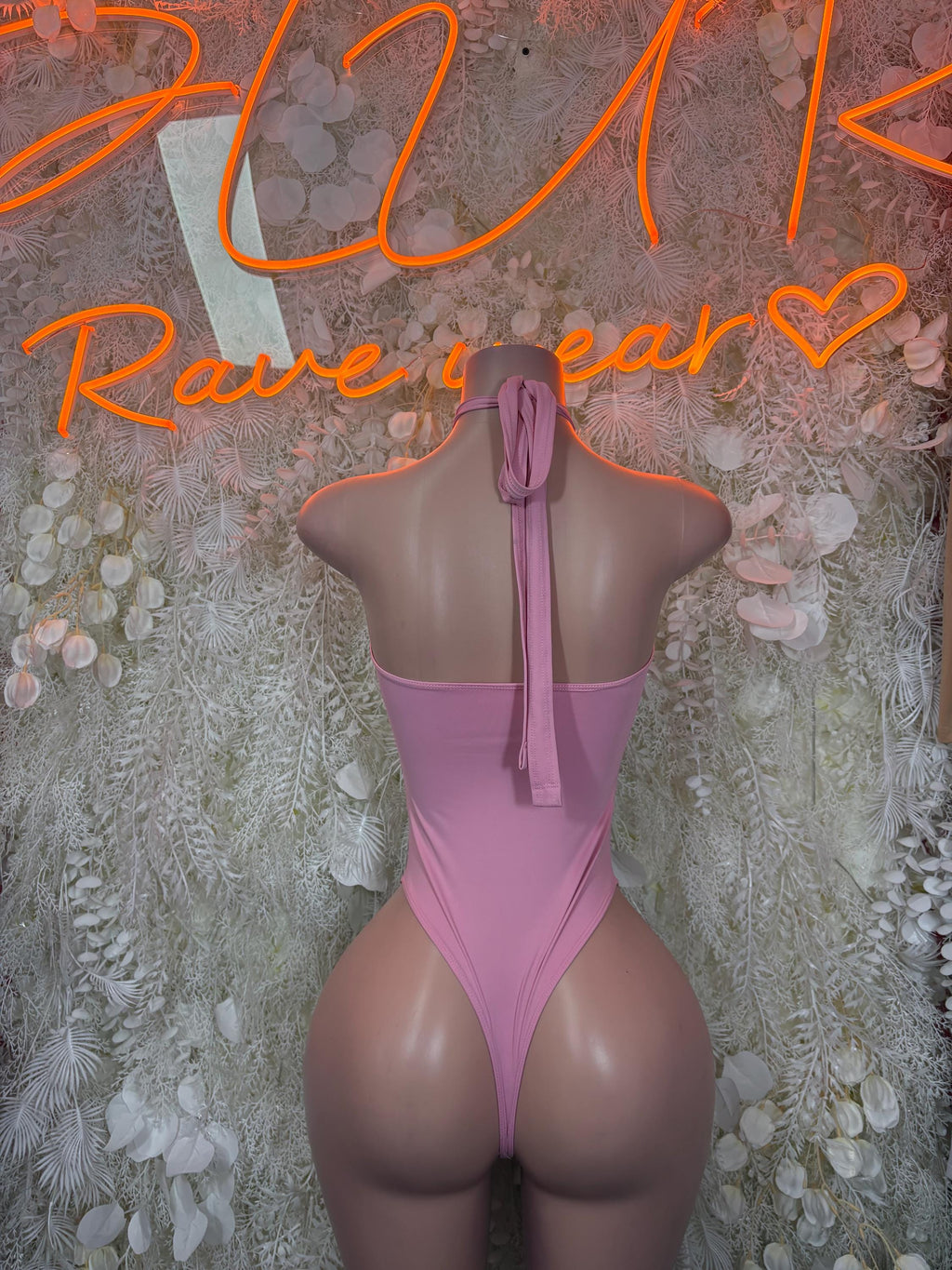 Pink halter cutout bodysuit with open back and tie straps, minimal-coverage fit