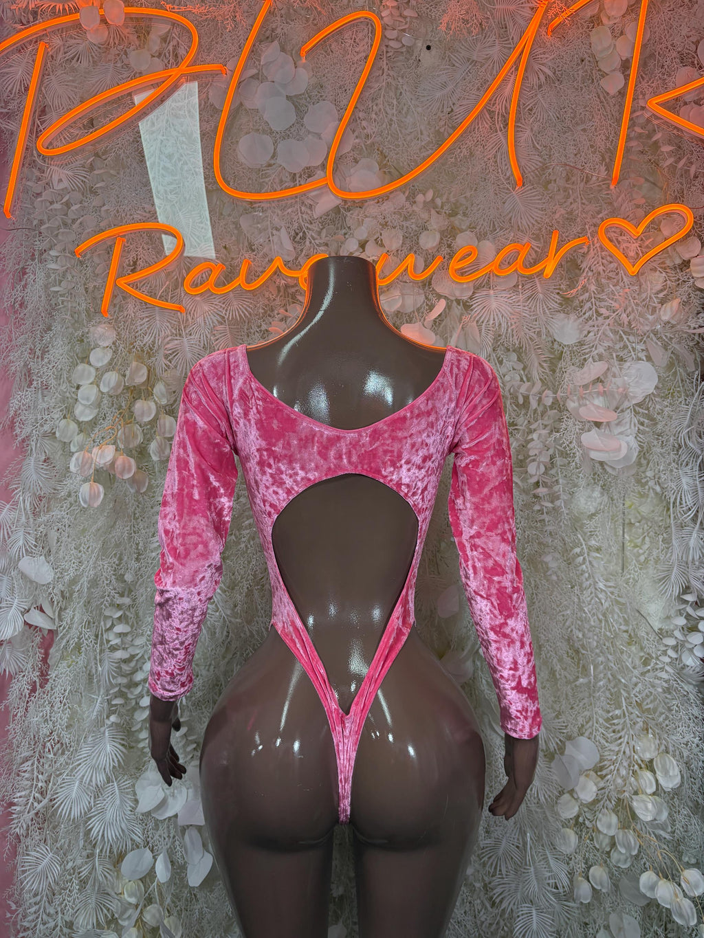 Pink velvet bodysuit with long sleeves and open V back cutout on mannequin