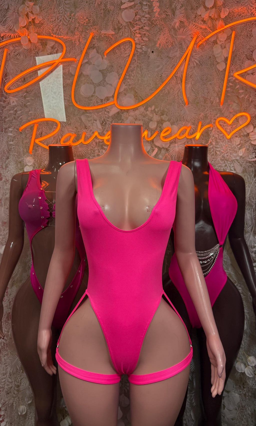 Pink one-piece bodysuit with halter neckline and side decorative accents