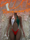 One-piece swimsuit with red center, green side panels, and white decorative neckline trim