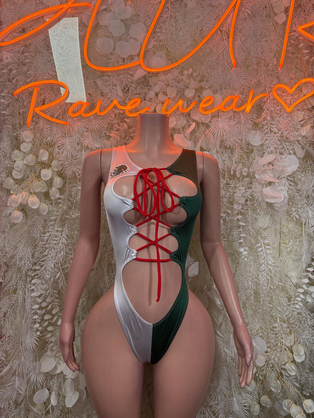 Green and white one-piece bodysuit with red lace-up front and high-cut sides