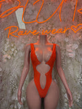 Orange one-piece bodysuit with deep V front and high-cut legs, metal ring at chest