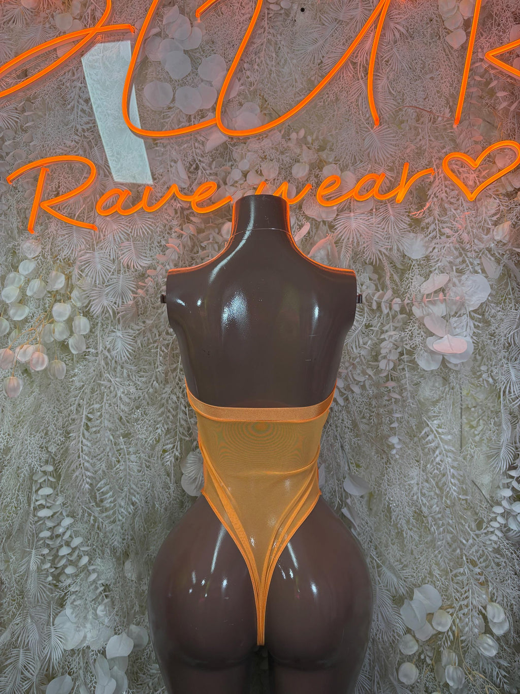 Orange one-piece bodysuit with open back and black sheer lower panels