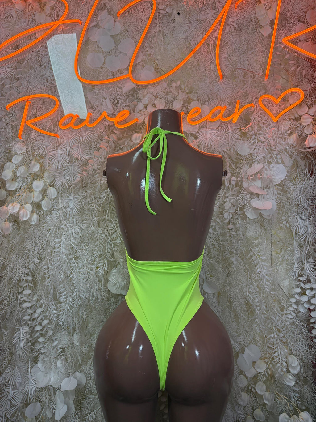 Neon green cutout bodysuit with halter back straps and high-cut legs.