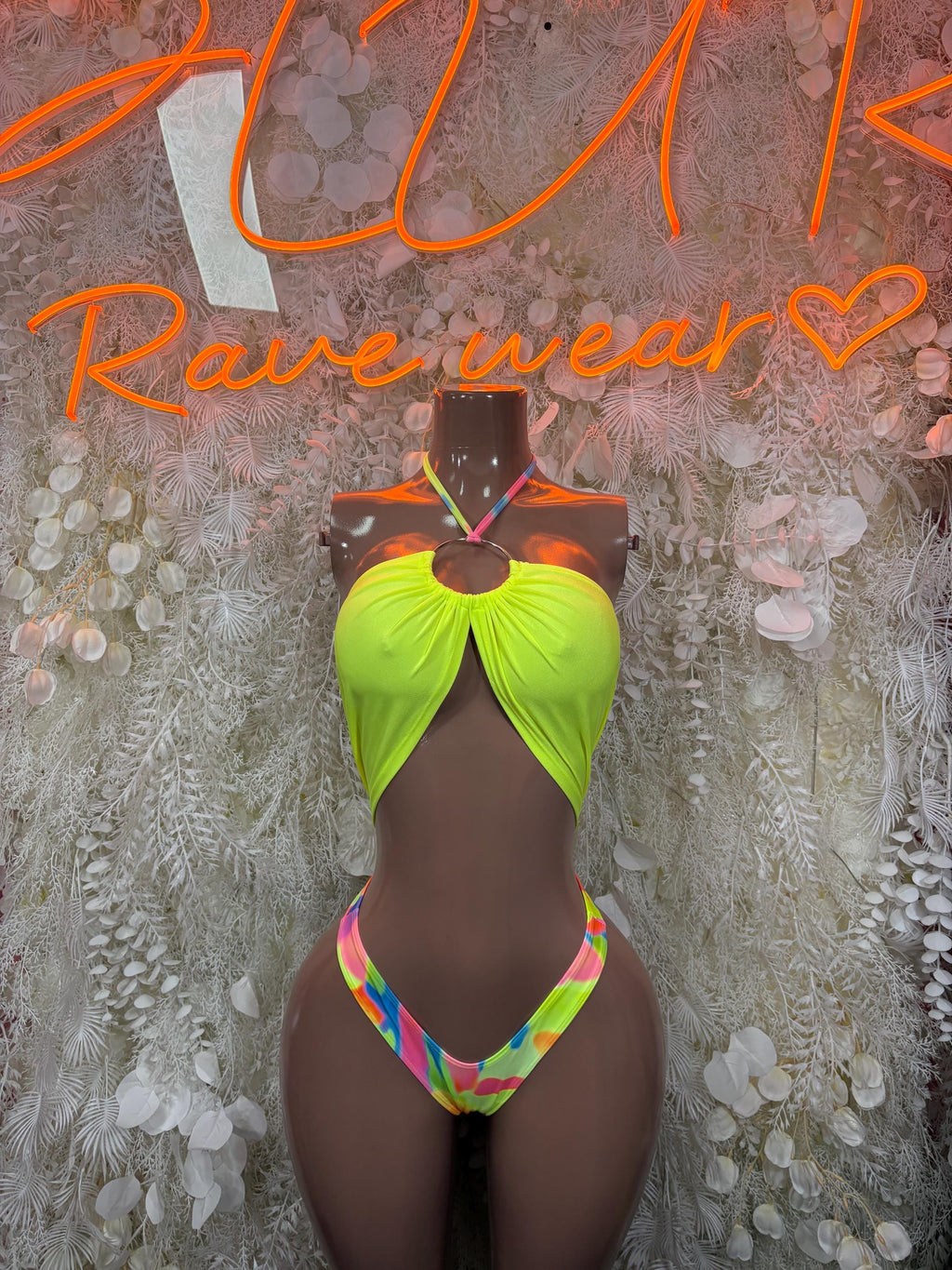 Neon green halter one-piece with rainbow trim, open chest, and high-cut bottom