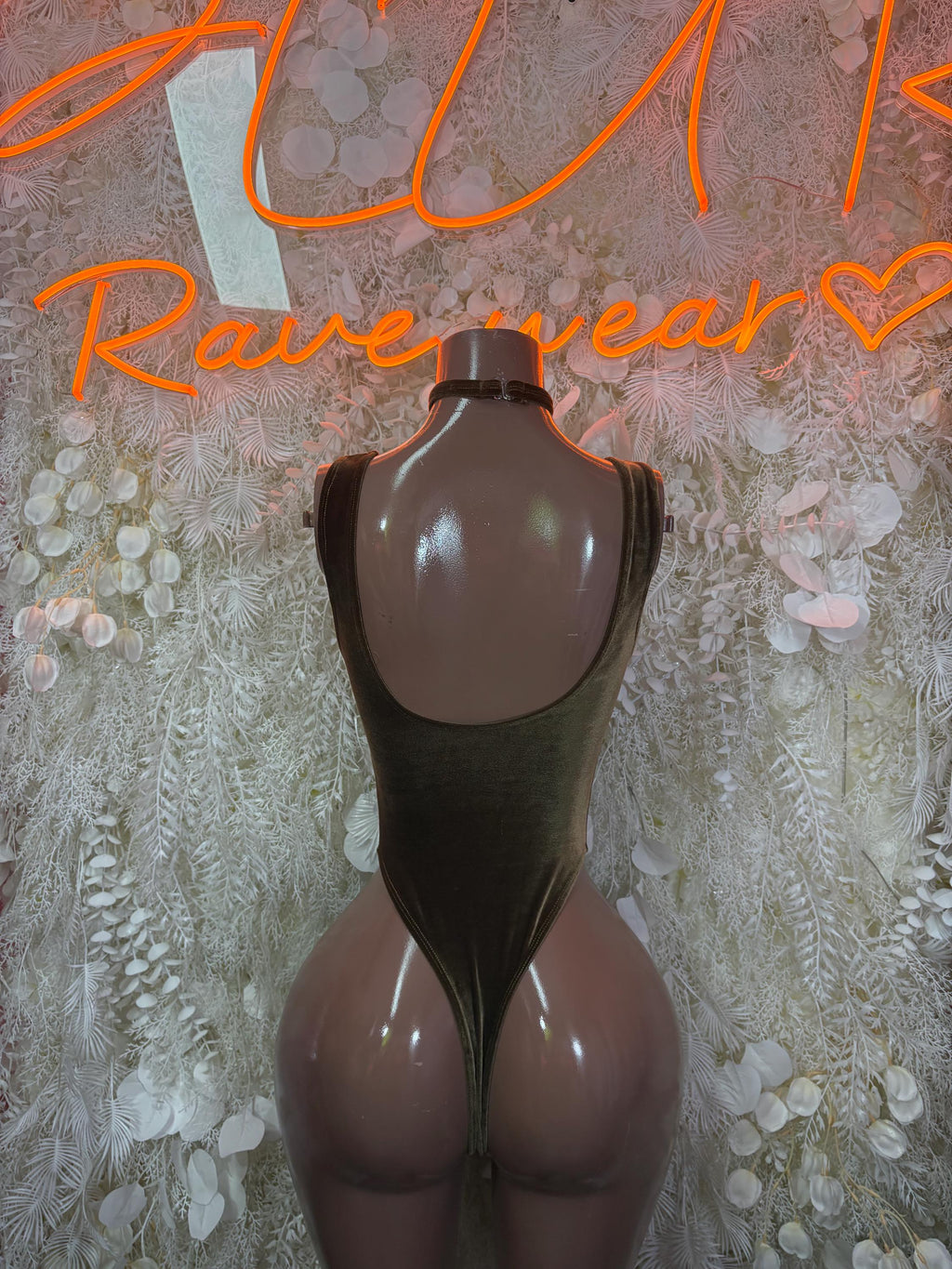 Dark olive-green velvet one-piece bodysuit with backless cutout and halter straps.