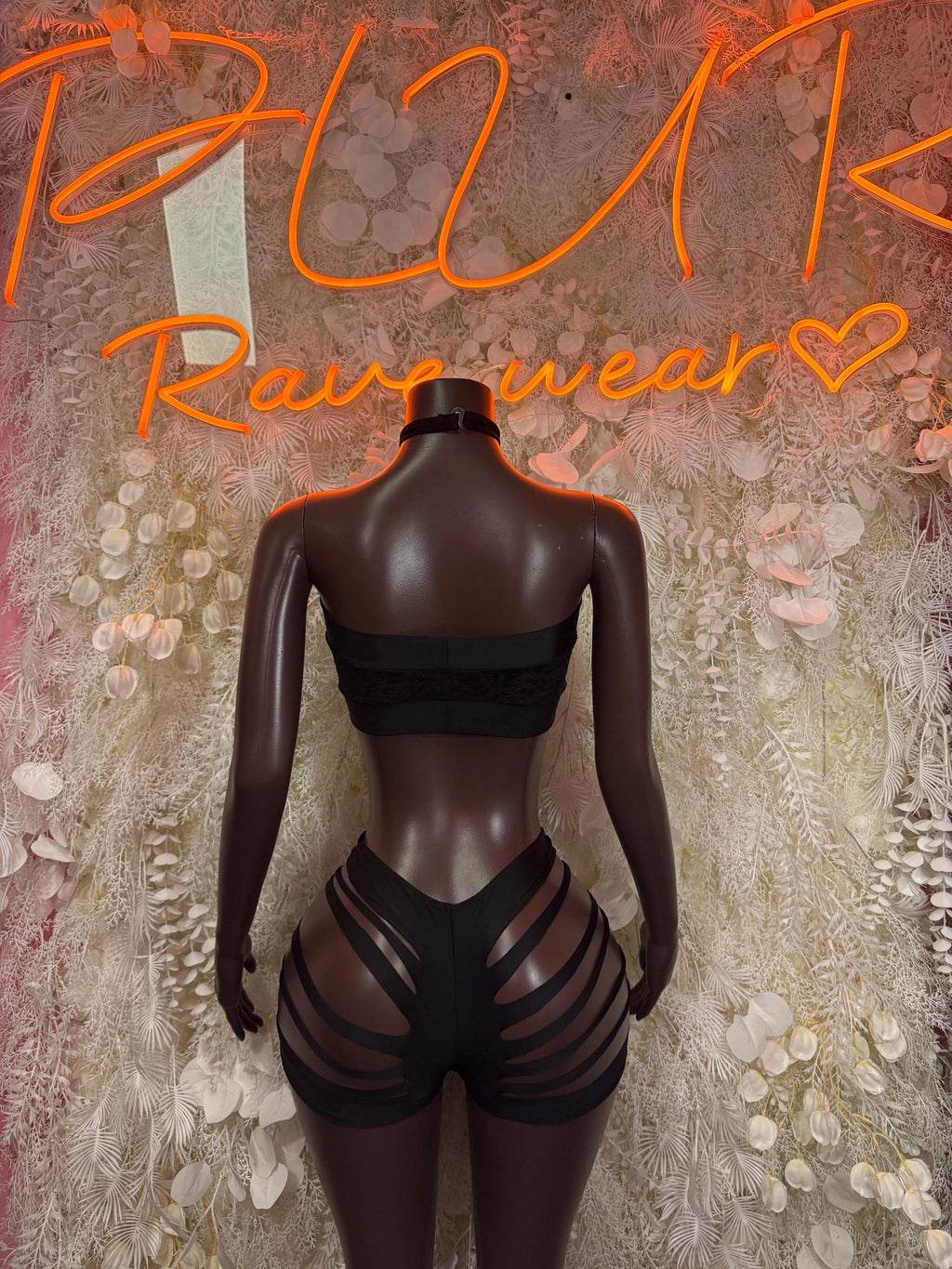 Black two-piece bodysuit with bandeau top and strappy striped shorts, back view