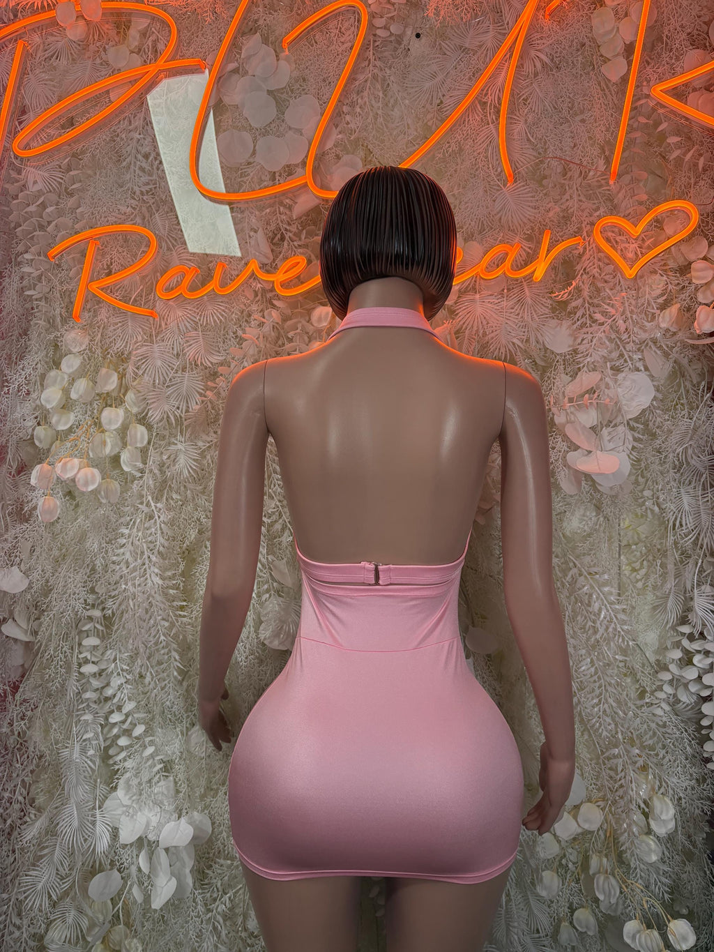 Pink mini dress with open back on model, crossover strap detail