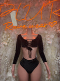 Black long-sleeve crop top and high-cut bottoms with lace-up front detail