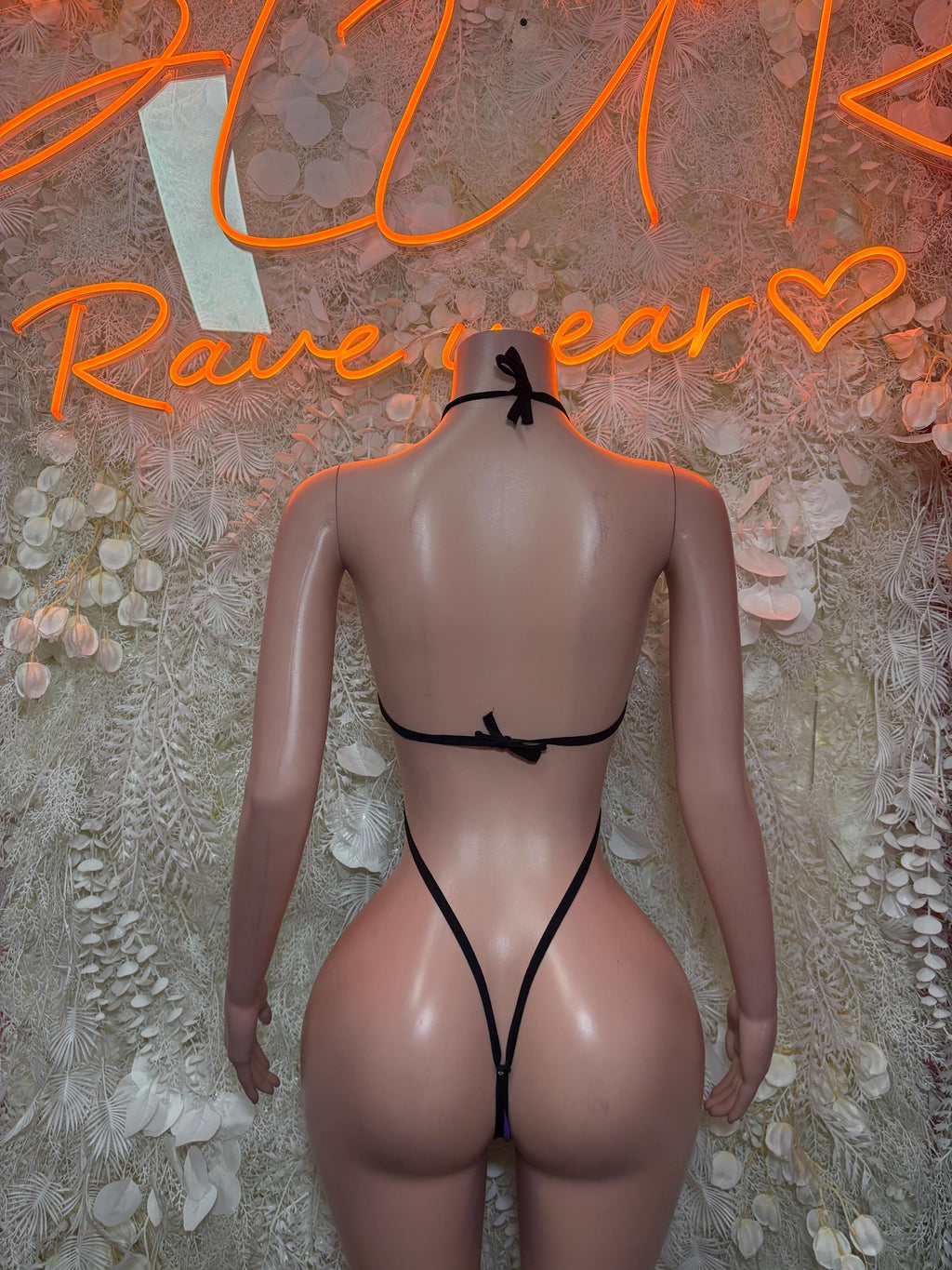 Back view of purple and black one-piece slingshot dance bodysuit, strappy back