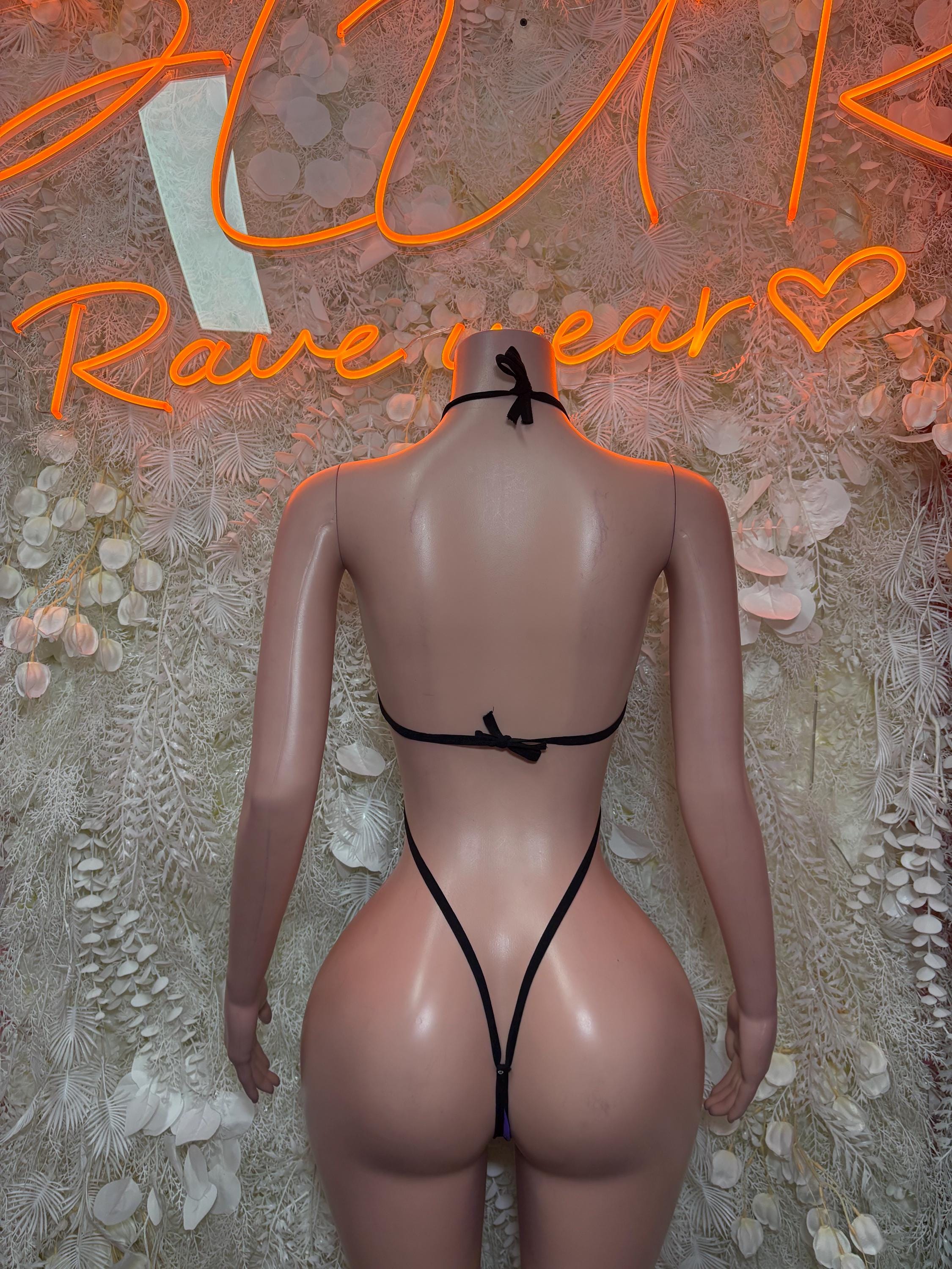 Back view of purple and black one-piece slingshot dance bodysuit, strappy back