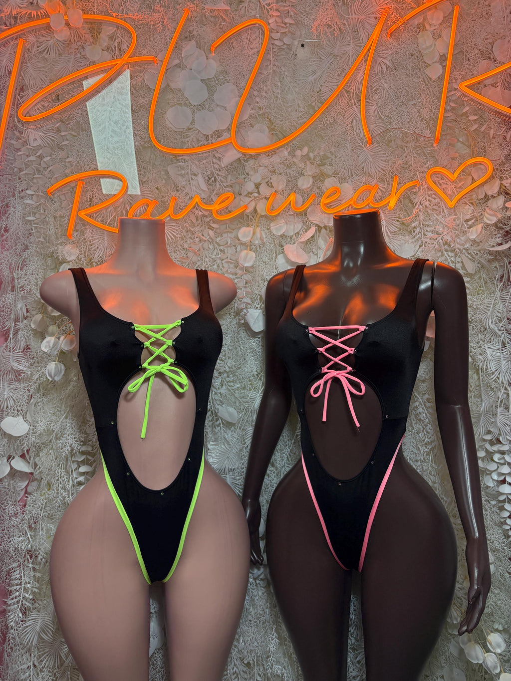 Black bodysuits with neon green and neon pink lace-up trim, double front view